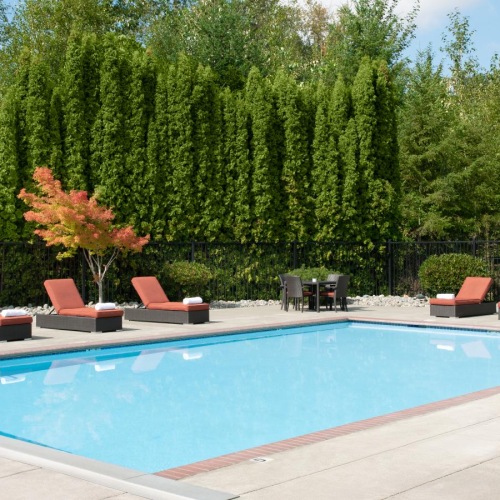 Relax and unwind poolside a swimming pool with chairs around it